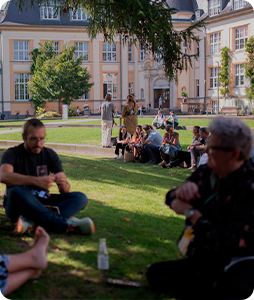 Personas reunidas en pequeños grupos al aire libre, disfrutando de una charla o actividad en un entorno de jardín.